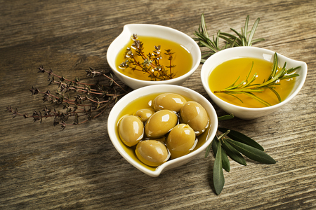 Olive oil with fresh herbs on wooden background.の写真素材