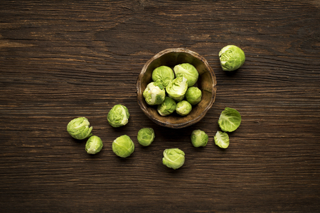 Bunch of fresh Brussels sprouts in a cup on wooden background.の写真素材