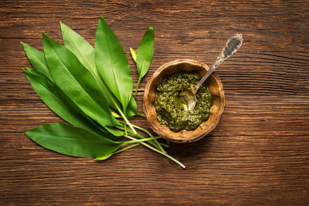 Wild garlic leafs and pesto on wooden background overhead shootの写真素材