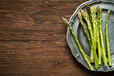 Fresh asparagus on a plate and wooden background.の写真素材