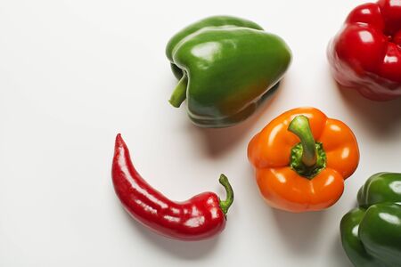 Red, green and orange bell peppers on white background.の写真素材