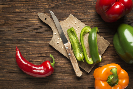 Red, green and orange bell peppers on wooden background.の写真素材