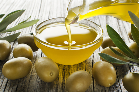 Bottle pouring virgin olive oil in a bowl close upの写真素材