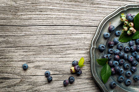 Juicy and fresh blueberries with green leaves on rustic tableの写真素材