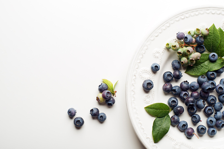 Juicy and fresh blueberries with green leaves on white backgroundの写真素材
