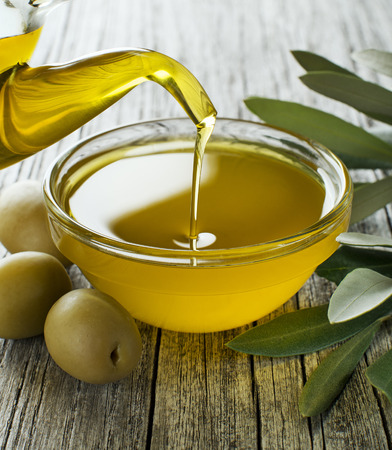 Bottle pouring virgin olive oil in a bowl close upの写真素材