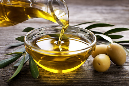 Bottle pouring virgin olive oil in a bowl close upの写真素材