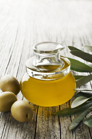Olive oil in a bottle on a wooden tableの写真素材