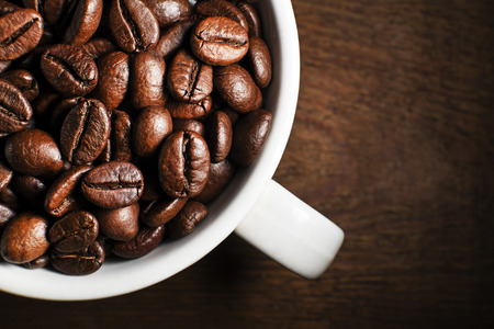 Fresh coffee beans in cup on wooden backgroundの写真素材