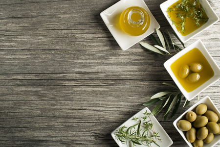Olive oil with fresh herbs on wooden backgroundの写真素材