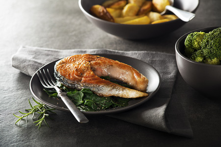 Grilled salmon steak with vegetables on dark background.の写真素材