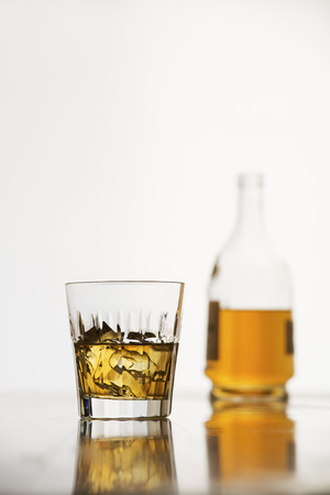 Whiskey with ice in glass and bottle on white backgroundの写真素材