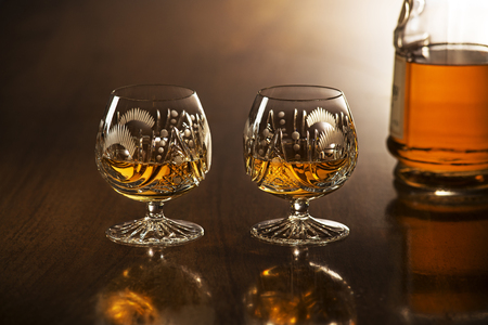 Cognac in glass with bottle on wooden tableの写真素材