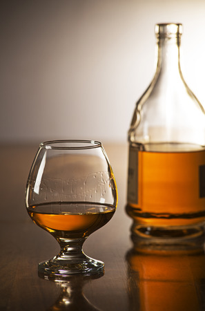 Whisky in glass with bottle on wooden tableの写真素材
