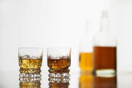Whiskey glasses with bottles on white backgroundの写真素材