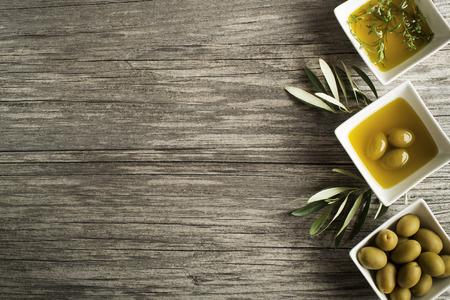 Olive oil with fresh herbs on wooden background.の写真素材