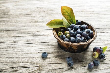 Fresh blueberries with green leaves on wooden backgroundの写真素材