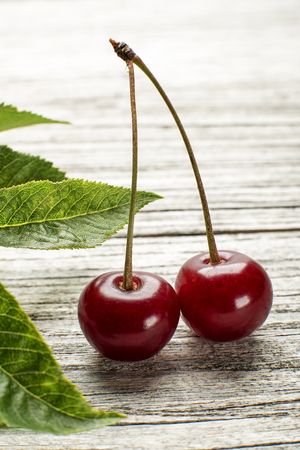 Cherries with green leaves on wooden backgroundの写真素材