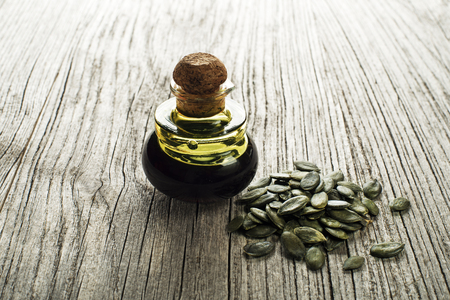 Dark pumpkin oil with seeds on wooden backgroundの写真素材