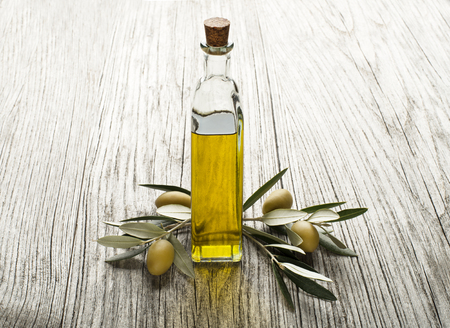 Olive oil and olive branch on the wooden tableの写真素材