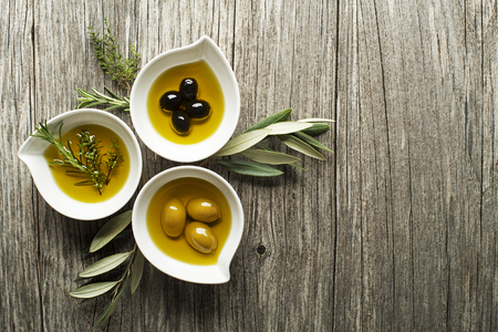 Olive oil with fresh herbs on wooden backgroundの写真素材