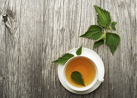 Cup of healthy herbal tea with nettle on wooden background.の写真素材