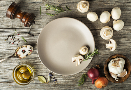 Mushrooms champignons with fresh ingredients on wooden backgroundの写真素材