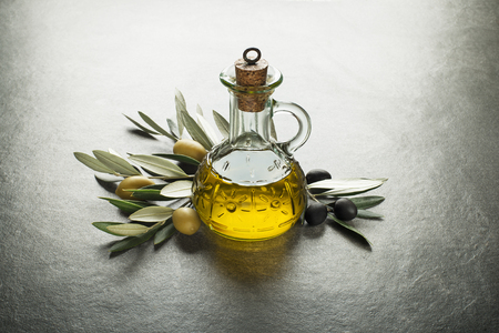 Olive oil and olive branch on the gray tableの写真素材