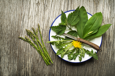 Spring food nettle, dandelion, wild garlic and asparagus on wooden backgroundの写真素材