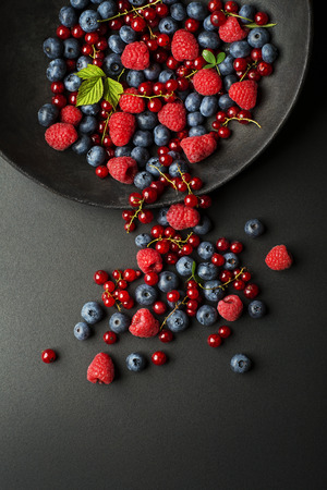 Mix of fresh berries in a bowl on black backgroundの写真素材