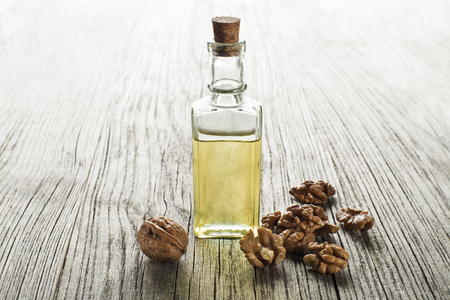 Walnut oil in a glass bottle on a wooden backgroundの写真素材