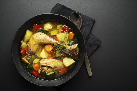 Chicken soup with vegetables in bowl on black backgroundの写真素材