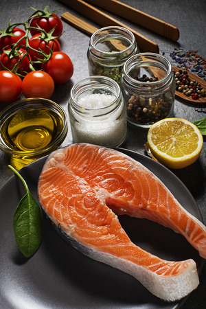 Selection of healthy food. Raw steak of salmon with fresh ingredients on gray background.の写真素材