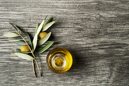 Olive oil and olive branch on wooden tableの写真素材