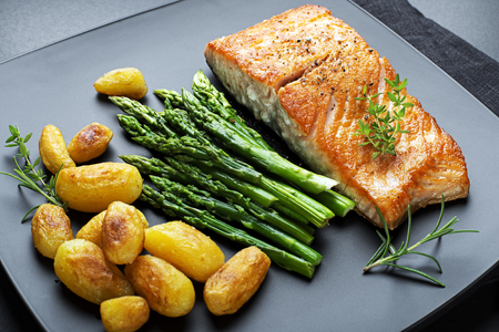Roasted salmon fillet with asparagus and potatoes on black backgroundの写真素材