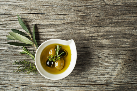 Olive oil with fresh herbs on wooden backgroundの写真素材
