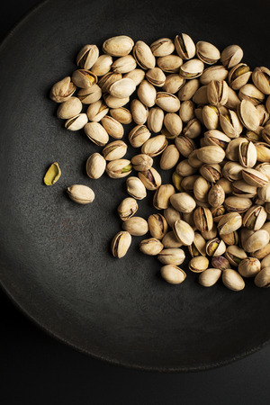 Bowl with pistachios on a black table backgroundの写真素材