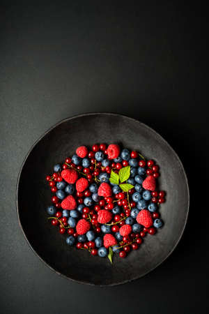 Mix of fresh berries in a bowl on black backgroundの写真素材