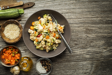 Risotto with chicken and vegetables served on wooden tableの写真素材