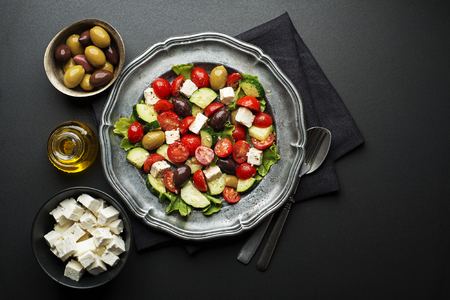 Salad with cheese and fresh vegetables on black background. Greek salad.の写真素材