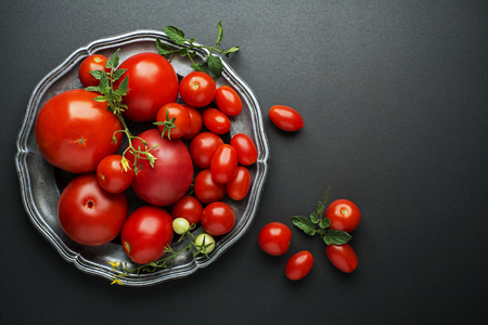 Fresh red tomatoes in a bowl on black background. Top viewの写真素材
