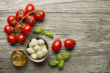 Fresh tomatoes and mozzarella cheese on wooden background. Top viewの写真素材
