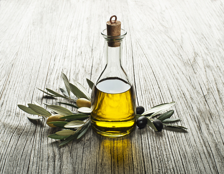 Olive oil and olive branch on a wooden backgroundの写真素材