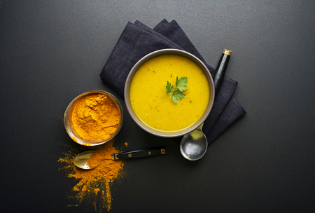 Healthy turmeric or curcuma cream soup on black backgroundの写真素材