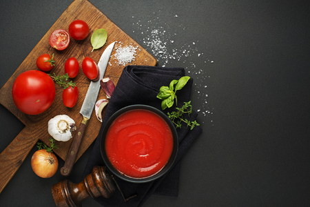 Fresh ingredients for cooking tomato sauce or soup on black background place for text. Vegan food vegetarian and healthy cooking concept.の写真素材