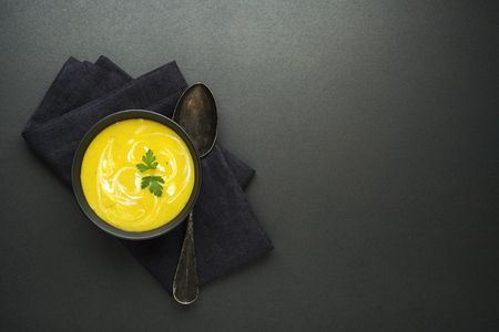 Healthy vegetable yellow cream soup on black background の写真素材