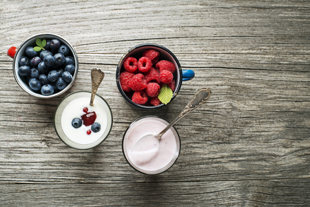 Yogurt with fresh berries in a glass jars with spoons の写真素材