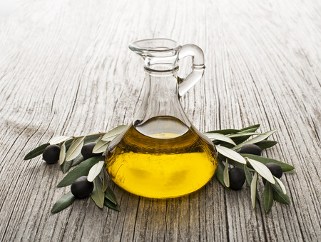 Olive oil and olive branch on wooden tableの写真素材
