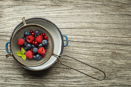 Mix of fresh berries in a bowl on wooden backgroundの写真素材