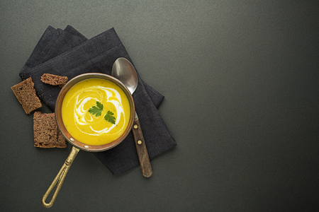 Healthy vegetable yellow cream soup on black backgroundの写真素材